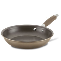 A nonstick frying pan with a metal base and a brown handle is isolated on a white background. The pan has two metal rivets connecting the handle to its body.
