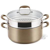 A brown nonstick pasta pot with a stainless steel strainer insert and a glass lid. The pot and strainer have double handles with silicone grips.