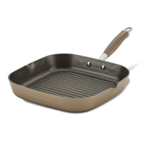 A square, non-stick grill pan with a ridged surface and a long handle, designed for stovetop cooking. The pan is beige on the outside and dark gray inside, with a sleek, modern design.