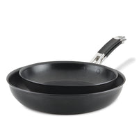 Two non-stick frying pans nested together, one slightly smaller than the other. Both pans have black interiors and exteriors, with shiny metal handles featuring black grips. The pans are positioned against a plain white background.
