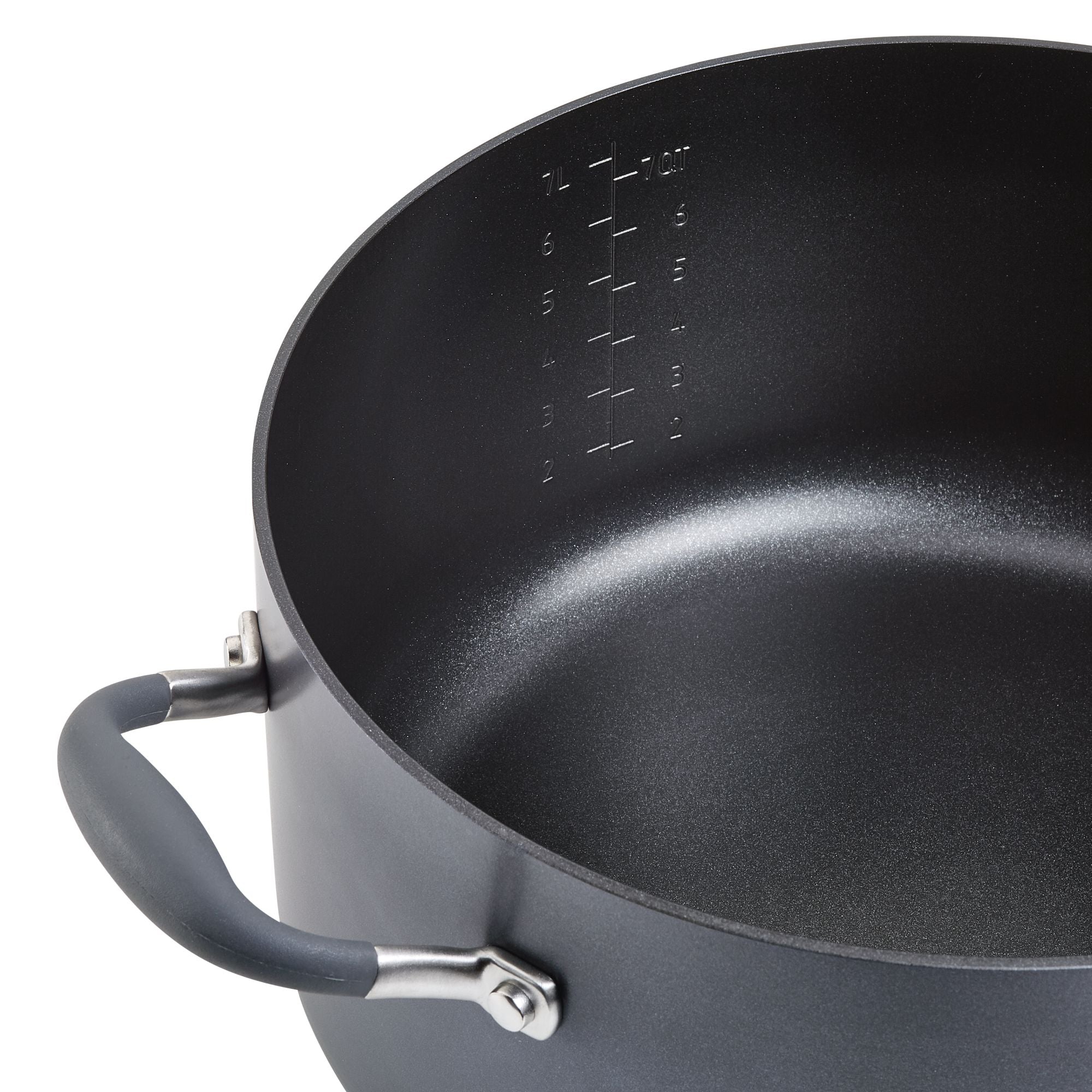 A large, dark-colored cooking pot with a non-stick interior is shown at an angle. It has measurement markings inside and features a handle with a rubber grip.