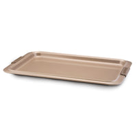 A rectangular gold-colored baking sheet with raised edges and handles on both sides, placed against a white background. The surface is smooth and slightly reflective.