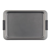 A rectangular gray baking sheet with non-stick surface and black silicone grips on the handles, set against a plain white background.