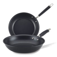 Two black non-stick frying pans are placed together. One is lying flat while the other is propped up behind it, angled to display both pans. They have matte finishes and stainless steel handles with black grips.