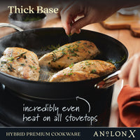 A hand cooks seasoned chicken breasts in the Anolon X 12-Inch Hybrid Nonstick Frying Pan with SearTech™ technology for even heat on all stovetops. Text: Thick Base, HYBRID PREMIUM COOKWARE, Anolon X.