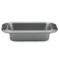 The Advanced 9 x 5-Inch Loaf Pan features wide side handles with black silicone grips, a heavy gauge steel build, and a durable nonstick finish, shown against a white background.