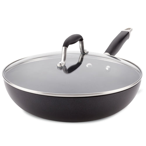 The Advanced Home 12-Inch Ultimate Stir Fry Pan features a sleek design with a shiny metal rim around its glass lid and hard-anodized construction. Its spacious, black surface is complemented by a raised arch handle for easy gripping, making it the ultimate pan for kitchen enthusiasts.