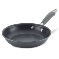 The Advanced Home Frying Pan with a curved handle is displayed. It is empty, set against a white background, and features two rivets securing the handle to the pan.