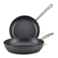 The Accolade 10 & 12-Inch Frying Pan Set features two sapphire-reinforced nonstick pans with metal handles; one pan lies flat as the other stands behind it, showcasing their precision forged interiors.