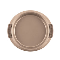 A 9-inch round cake pan labeled with Advanced features brown silicone grips on either side, offering easy handling and perfect baking results. The interior is smooth and metallic, ensuring nonstick performance when viewed from the top down.