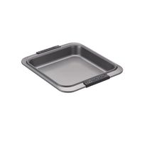 Resting on a white background, the square gray metal baking pan with black silicone handles from Advanced's 5-Piece Bakeware Set is perfect for creating delicious banana nut bread. As part of a nonstick bakeware collection, it guarantees easy release and cleanup, making it an ideal choice for baking enthusiasts.