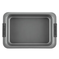 The Advanced 9 x 13-Inch Cake Pan with Lid is a rectangular, nonstick bake pan with wide gray handles embossed with the brand name. It is shown empty from a top-down view.