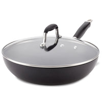 The Advanced 12-Inch Covered Ultimate Pan is a black nonstick stir fry pan with a long handle and matching glass lid with metal and black handle, ideal for one-pan meals, shown against a white background.