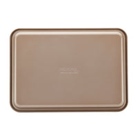 Part of the 3-Piece Gourmet Cookie Pan Set by Gourmet, this beige rectangular metal baking tray boasts a smooth nonstick surface ideal for homemade cookies. It features a raised lip around its edges and is presented against a plain white background.