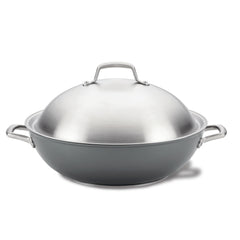 The Accolade 13.5-Inch Wok with Lid, featuring a large round design in stainless steel with a nonstick surface, is crafted using Precision Forge technology. It includes a shiny dome-like lid and two side handles and is showcased against a plain white background.