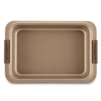 The Advanced 9 x 13-Inch Cake Pan with Lid features wide edges, brown silicone handles, a metallic gold finish, smooth nonstick interior, and a stylish design for easy handling.