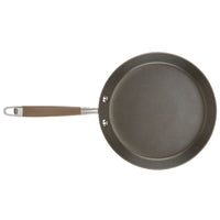 Introducing the 9.5-Inch Crepe Pan by Advanced Home: This nonstick frying pan, with its sleek gray design and smooth surface, makes cooking a breeze. The brown handle is securely attached with two rivets and includes a metal loop at the end for convenient hanging.