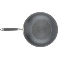 A top-down view of the Advanced Home 12-Inch Stir Fry pan with a metal handle highlights its black, circular patterned bottom. The Infinity Slide nonstick coating guarantees effortless cooking. Centrally embossed with the brand name, this hard-anodized frying pan is a kitchen essential.