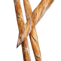 Three crusty baguettes, each with a golden-brown exterior, are arranged in an overlapping pattern on an Advanced Three Channel Baguette Tray. Their diagonal cuts and rustic texture stand out against the white background.