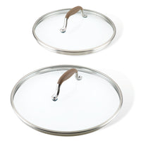 Two glass lids from the Lid Set, featuring stainless steel rims and SureGrip® brown handles, are set against a white background. One lid is larger than the other with elegantly curved handles. These replacement lids from the Advanced Home collection perfectly blend functionality with style.